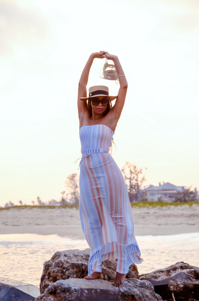 woman in white and pink stripe dress wearing white sunglasses standing on beach during daytime